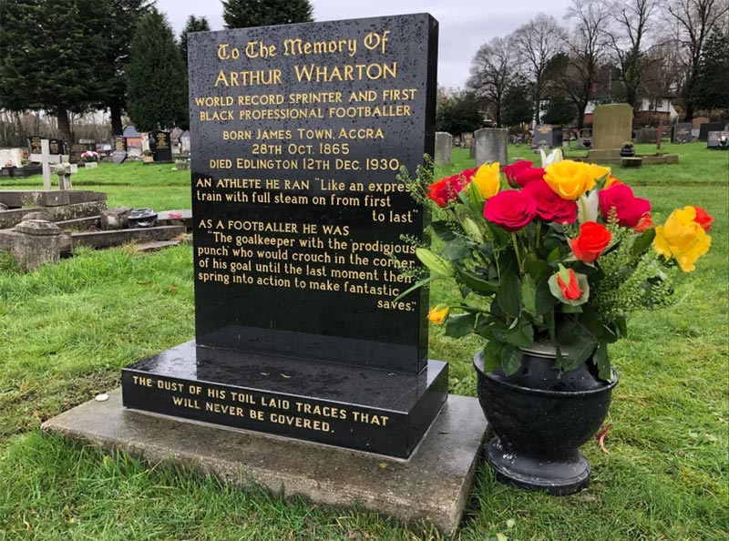 Grave headstone with yellow and red flowers in an adjacent vase